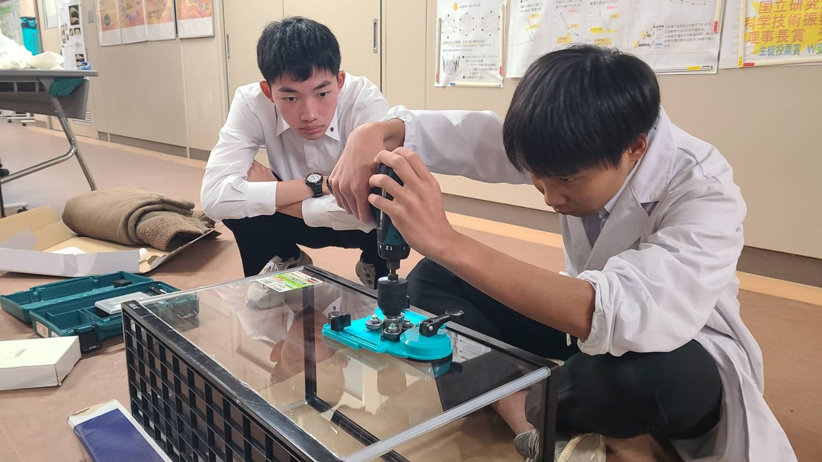 高校生がドライバーを使って水槽を組み立てている